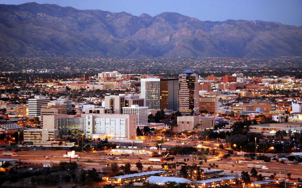 A cityscape at dusk with mountains in the background
