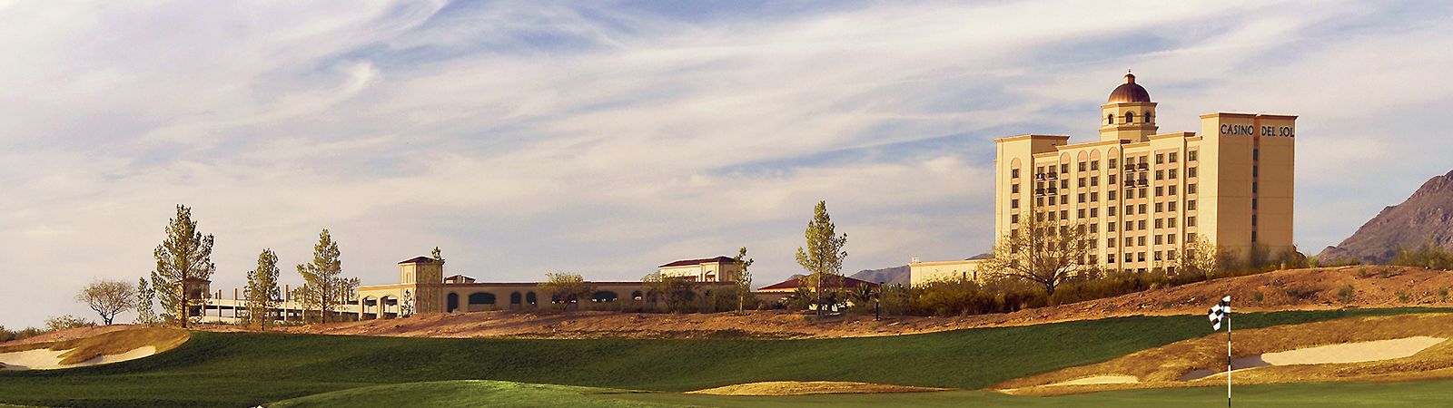 A large hotel building with a golf course in front of it.