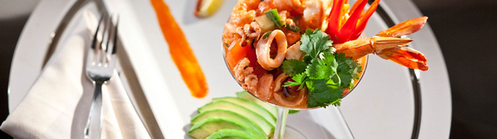 a plate of ceviche with shrimp, avocado, and cilantro