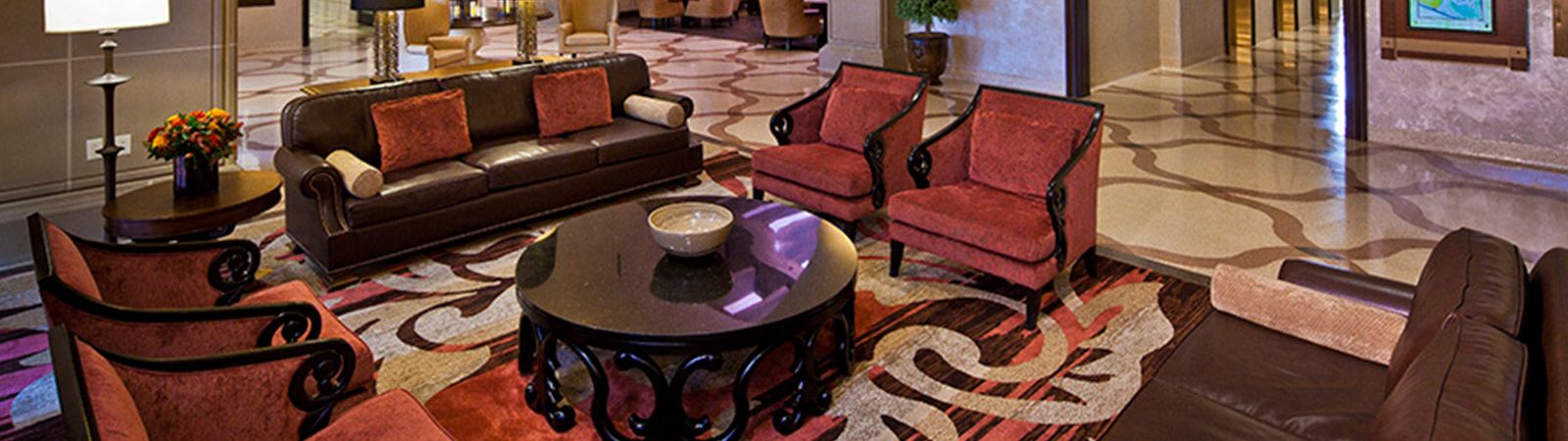 A wide view of a hotel lobby with a seating area, coffee table, and decorative elements.