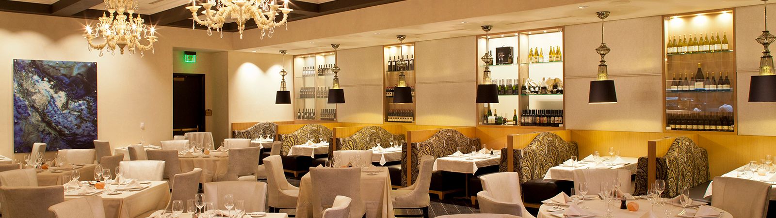 A fine dining restaurant with white tablecloths, wine glasses, and chandeliers.