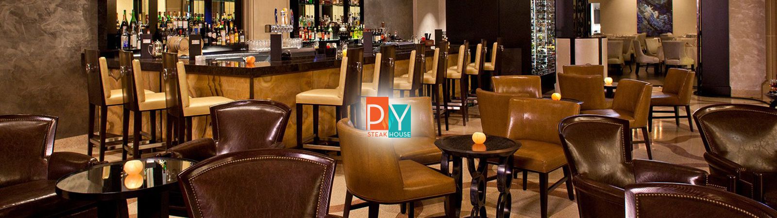 A dimly lit bar with a long counter and stools, and several tables with chairs, in a lounge-like setting.