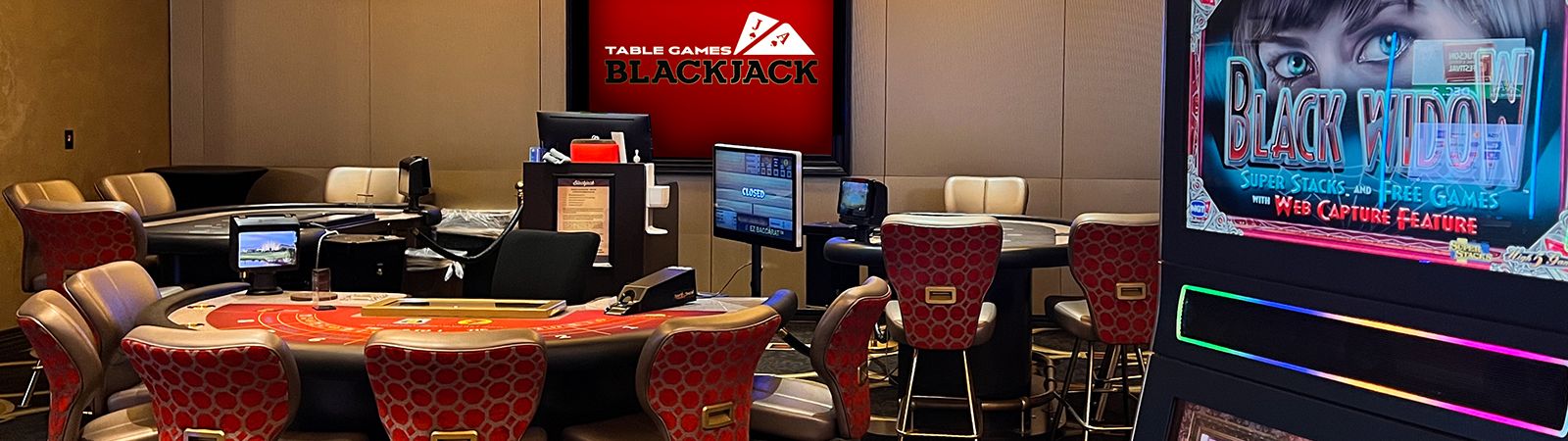 A casino lounge with a blackjack table and video screens.